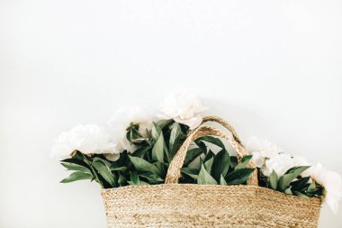 Beyaz arka plan üzerinde beyaz şakayık çiçekleri ile hasır çanta.