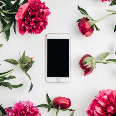 Beyaz arka plan üzerinde pembe peonies çiçeklerin çerçevede cep telefonu. Düz yatıyordu, en iyi görünümü kadar sahte.
