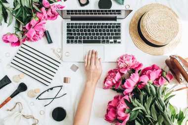 Düz yatıyordu ofis büro dizüstü, pembe şakayık çiçekleri, kozmetik, aksesuarları ile tarz. Bilgisayarda çalışan kadın. Moda ya da güzellik blog arka plan.