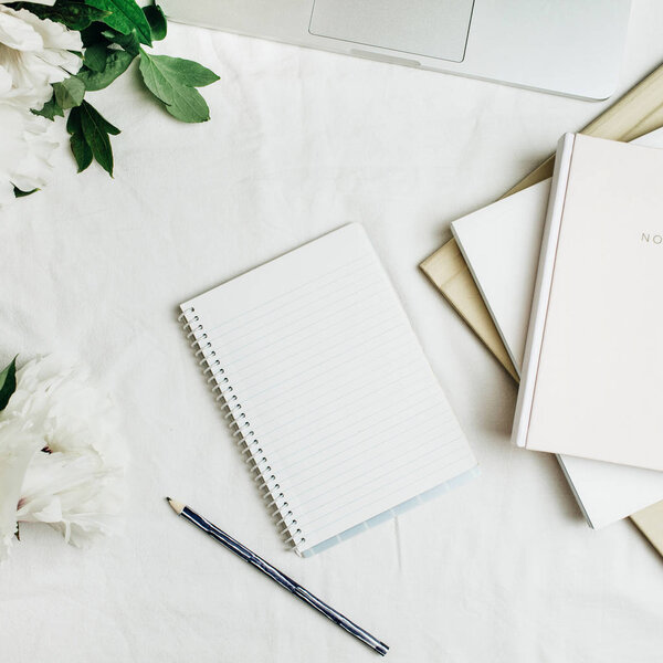 Квартира лежала домашний стол офиса с ноутбуком, ноутбук, белые пионы букет цветов на белом фоне. Вид сверху
.