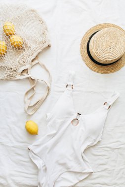Yaz Bayan mayo, saman, limon beyaz battaniye üzerinde dize çantada. Arka plan düz yatıyordu, en iyi görünüm çok az yaşam tarzı moda giysiler.