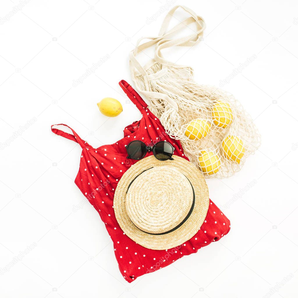 Summer female fashion stylish composition. Red dress, straw, string bag, sunglasses and lemons on white background. Flat lay, top view.