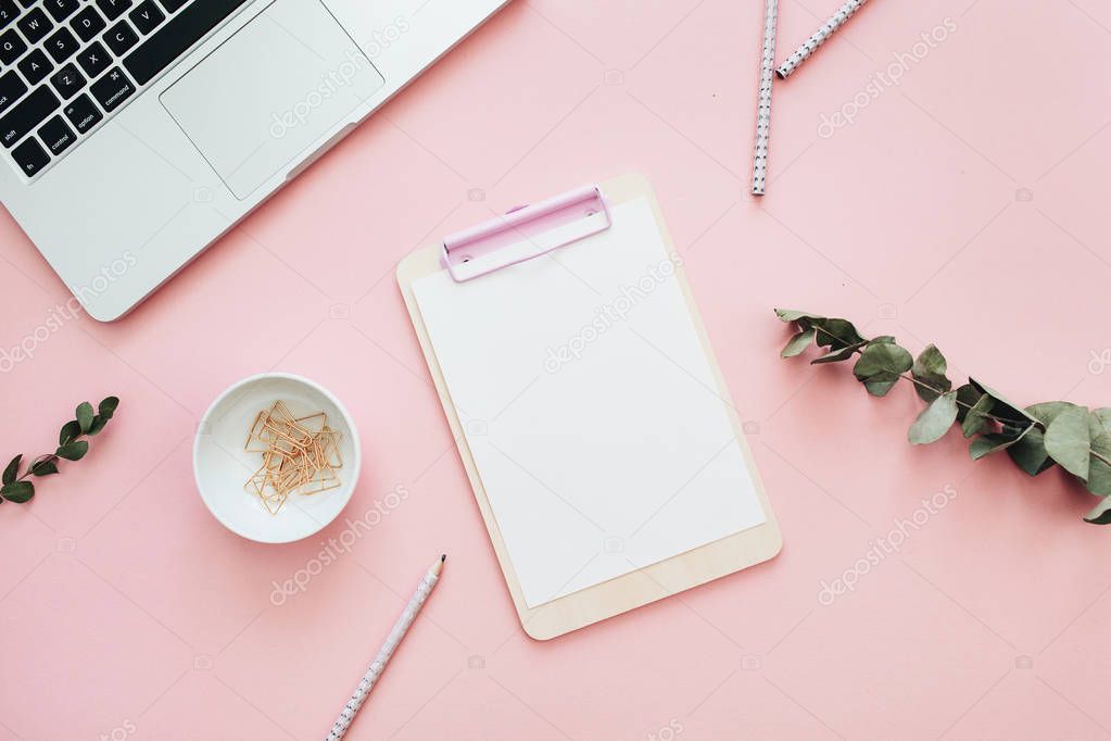 Flat lay home office desk workspace frame with space for text of laptop, clipboard and eucalyptus branches on pink background. Minimal blog hero header mock up with view from above.