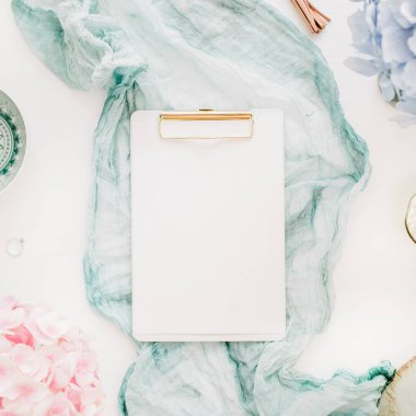 Ev ofis masası clipboard ile kopya alanı, Turkuaz battaniye, pastel renkli ortanca çiçek buketi, kadın moda aksesuar beyaz arka plan üzerinde bulunmaktadır. Düz yatıyordu, en iyi görünümü çalışma alanı mockup.