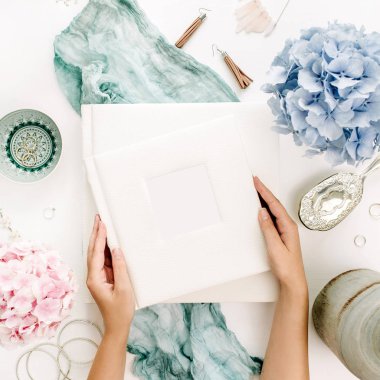 Kadın elele tutuşun aile düğün fotoğraf albümü, pastel renkli ortanca çiçek buketi, Turkuaz battaniye, dekorasyon, beyaz arka plan üzerinde moda aksesuarları. Düz yatıyordu, en iyi görünümü.