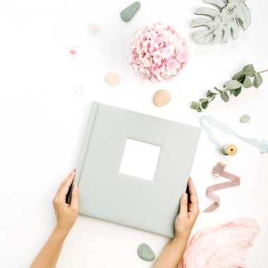 Eller düğün veya aile fotoğraf albümü tutun. Ortanca çiçek buketi, okaliptüs şube, pastel pembe battaniye, monstera yaprak plaka üzerinde beyaz arka plan ile kompozisyon. Düz yatıyordu, en iyi görünümü.