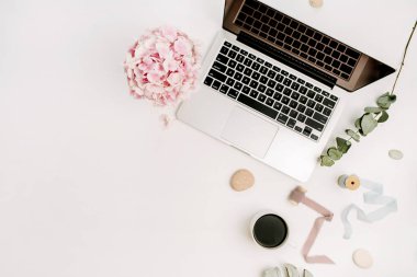 Modern ev ofis resepsiyon çalışma alanı dizüstü bilgisayar, pembe ortanca çiçek buketi, kahve fincanı, okaliptüs şube, monstera yaprak plaka ve aksesuar beyaz arka plan üzerinde. Düz yatıyordu, en iyi görünümü.
