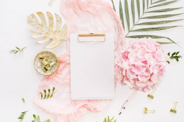 Modern ev ofis resepsiyon çalışma alanı boş kağıt Pano, pembe ortanca çiçek buketi, tropikal palmiye yaprağı, pastel battaniye, monstera yaprak plaka ve beyaz arka plan üzerinde aksesuarları ile. Düz yatıyordu, en iyi görünümü altın mockup gül.