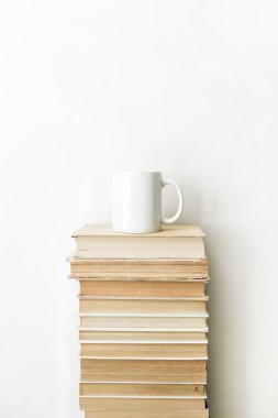 Books pile and coffee mug on white background. Minimal reading concept. clipart