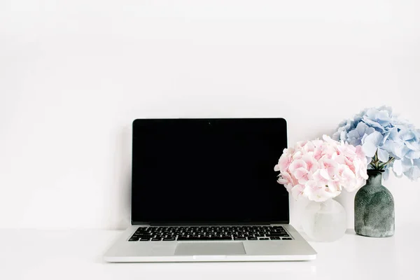 空白屏幕膝上型电脑和粉红色和蓝色绣球花花束在白色背景 最小家庭办公台样机 — 图库照片