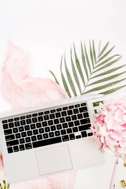Kadınsı ev ofis büro dizüstü bilgisayar, pembe ortanca çiçek buketi, pastel battaniye, monstera yaprak plaka ve aksesuar beyaz arka plan üzerinde. Çalışma alanı düz yatıyordu, üst görüntüle.