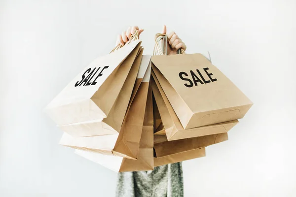 Black Friday sales discount concept. Young woman hold craft paper bags with word Sale on white background.