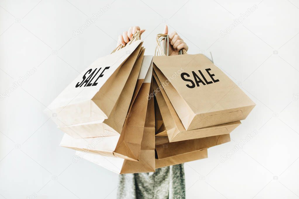 Black Friday sales discount concept. Young woman hold craft paper bags with word Sale on white background.