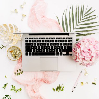 Modern ev ofis resepsiyon çalışma alanı dizüstü bilgisayar, pembe ortanca çiçek buketi, tropikal palmiye yaprağı, pastel pembe battaniye, monstera yaprak plaka ve aksesuar beyaz arka plan üzerinde. Düz yatıyordu, en iyi görünümü.