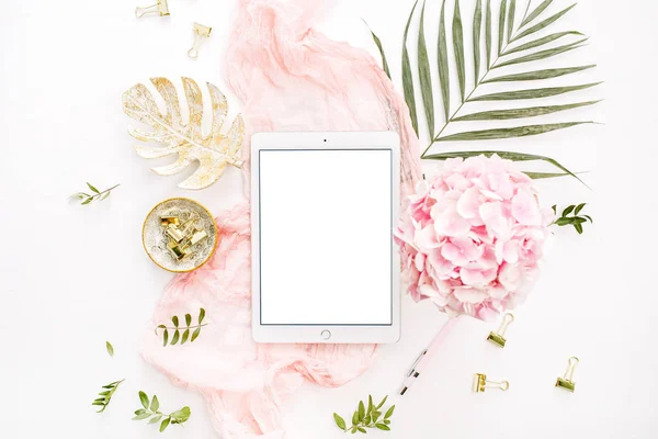 Boş ekran tablet, pembe ortanca çiçek buketi, tropikal palmiye yaprağı, pastel battaniye, monstera yaprak tabak ve aksesuar beyaz arka plan üzerinde. Düz yatıyordu, en iyi görünümü gül altın ev ofis resepsiyon çalışma alanı mockup.