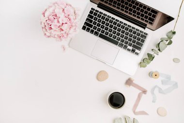 Ev ofis resepsiyon çalışma alanı dizüstü bilgisayar, pembe ortanca çiçek buketi, kahve fincanı, okaliptüs şube ve aksesuar beyaz arka plan üzerinde. Düz yatıyordu, en iyi görünümü.