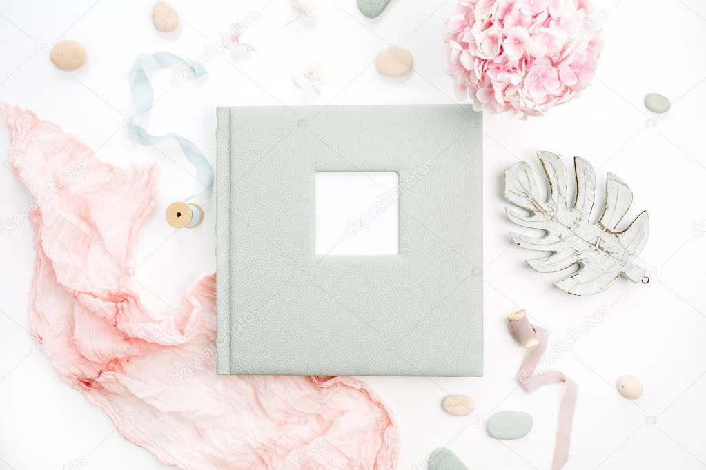 Family or wedding photo album with blank space for text, hydrangea flower bouquet, pink blanket, decoration on white background. Flat lay, top view.