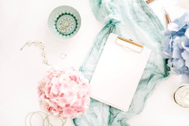 Ev ofis masası clipboard ile kopya alanı, Turkuaz battaniye, pastel renkli ortanca çiçek buketi, kadın moda aksesuar beyaz arka plan üzerinde bulunmaktadır. Düz yatıyordu, en iyi görünümü çalışma alanı mockup.