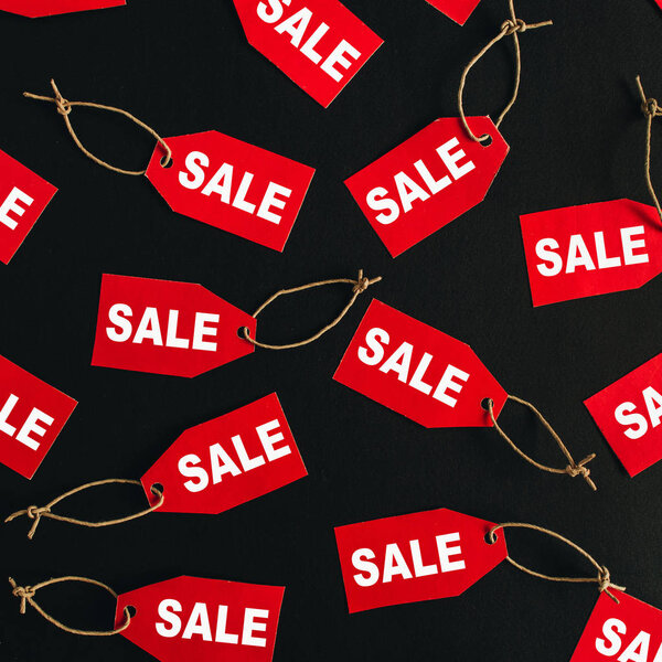Состав скидок на распродажи "черной пятницы". Красные бирки со словом SALE на чёрном фоне. Плоский, вид сверху
.