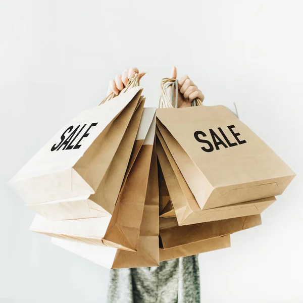 Black Friday sales discount concept. Young woman hold craft paper bags with word Sale on white background.