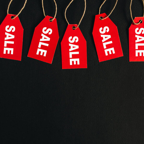 Состав скидок на распродажи "черной пятницы". Красные бирки со словом SALE на чёрном фоне. Заголовок героя. Плоский, вид сверху
.