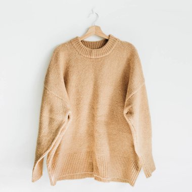 Kadın yün kazak, beyaz duvar askı üzerine. Kadın moda giysiler kavramı.