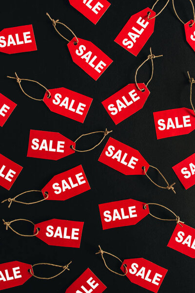 Состав скидок на распродажи "черной пятницы". Красные бирки со словом SALE на чёрном фоне. Плоский, вид сверху
.