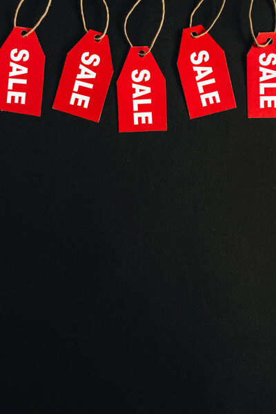 Состав скидок на распродажи "черной пятницы". Красные бирки со словом SALE на чёрном фоне. Заголовок героя. Плоский, вид сверху
.