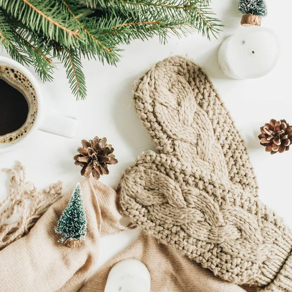 Coffee mug, wreath frame of fir branches, knitted mittens, beige blanket and decorations. Christmas / New Year holiday composition. Flat lay, top view.