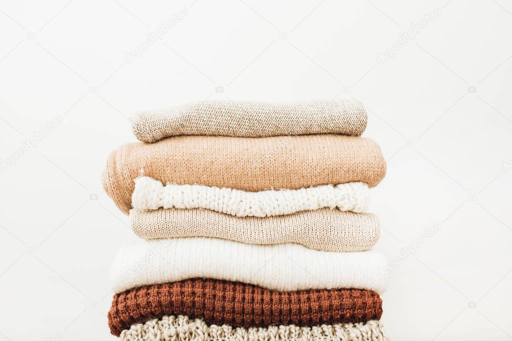 Woolen sweaters and pullovers stack on white background. Woman fashion clothes on white background.