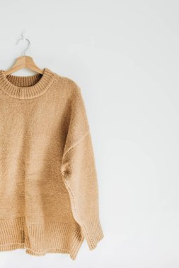 Kadın yün kazak, beyaz duvar askı üzerine. Kadın moda giysiler kavramı.