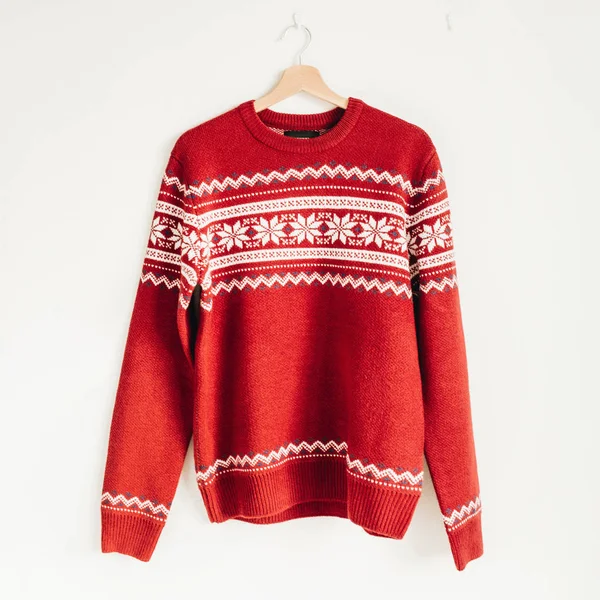 Warm red Christmas sweater on hanger on white background.