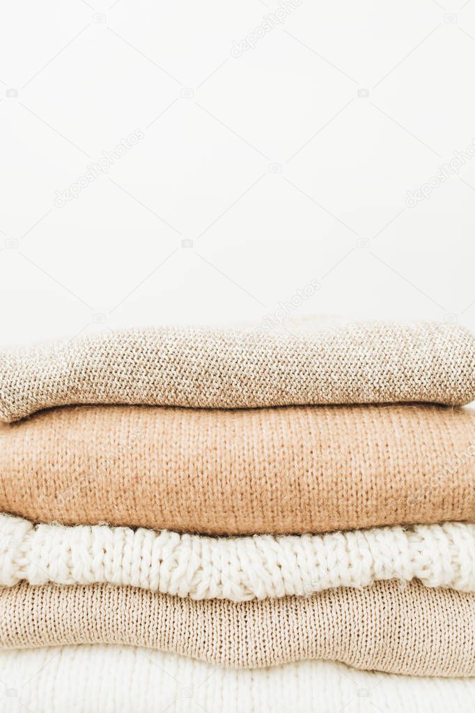 Warm woolen sweaters and pullovers stack on white background. Woman fashion clothes on white background.