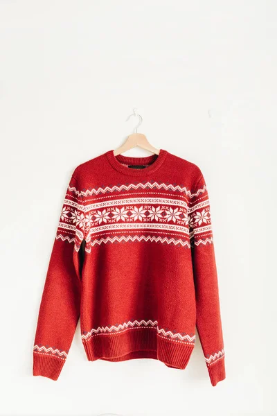 Warm red sweater on hanger on white background. Christmas, New Year, Winter fashion concept.