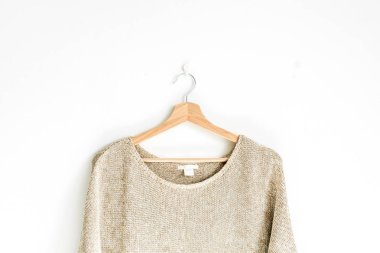 Kadın kazak, beyaz duvar askı üzerinde. Kadın moda giysiler kavramı.