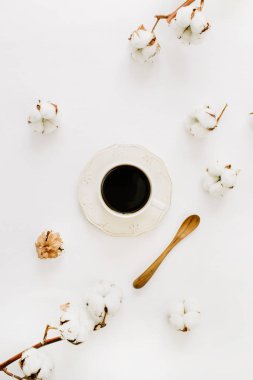 Kahve fincanı, tahta kaşık ve pamuk tomurcukları beyaz arka plan üzerinde düz yatıyordu. Üstten görünüm.