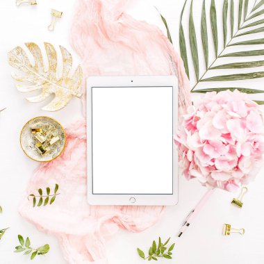 Boş ekran tablet, pembe ortanca çiçek buketi, tropikal palmiye yaprağı, pastel battaniye, monstera yaprak tabak ve aksesuar beyaz arka plan üzerinde. Düz yatıyordu, en iyi görünümü gül altın ev ofis resepsiyon çalışma alanı mockup.
