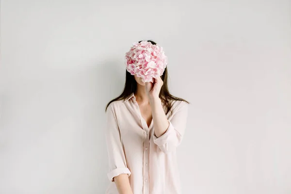 年轻女子举行粉红色绣球花花束在白色背景 — 图库照片