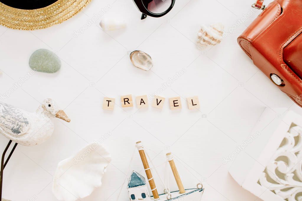Word Travel, bird figurine, toy boat, retro camera, seashells and straw hat on white background. Flat lay, top view lifestyle blog hero header.
