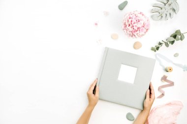 Eller düğün veya aile fotoğraf albümü tutun. Ortanca çiçek buketi, okaliptüs şube, pastel pembe battaniye, monstera yaprak plaka üzerinde beyaz arka plan ile kompozisyon. Düz yatıyordu, en iyi görünümü.