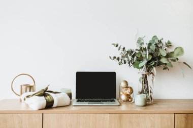 Blogger, serbest ev ofis resepsiyon çalışma alanı. Sahte ahşap masaüstü ekranı olan dizüstü bilgisayar okaliptüs kokulu, hediye kutusu, mum beyaz zemin üzerine dekore edilmiştir. Blog, Web sitesi, sosyal medya kahraman başlık.