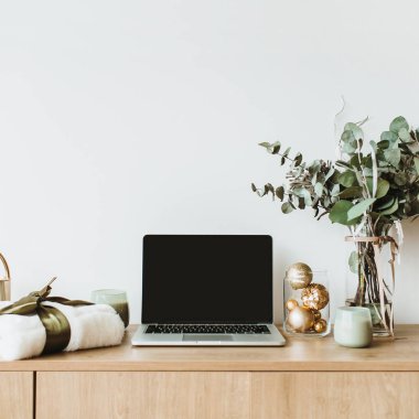 Blogger, serbest ev ofis resepsiyon çalışma alanı. Sahte ahşap masaüstü ekranı olan dizüstü bilgisayar okaliptüs kokulu, hediye kutusu, mum beyaz zemin üzerine dekore edilmiştir. Blog, Web sitesi, sosyal medya kahraman başlık.