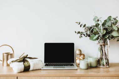 Blogger, serbest ev ofis resepsiyon çalışma alanı. Okaliptüs kokulu, hediye kutusu, beyaz zemin üzerine mumlar laptop sahte ahşap masaüstü ekranı ile dekore edilmiş.