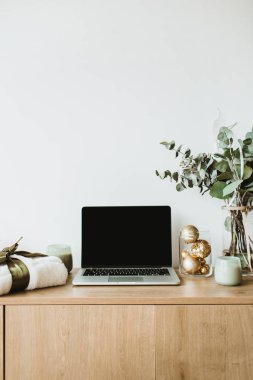 Blogger, serbest ev ofis resepsiyon çalışma alanı. Okaliptüs kokulu, hediye kutusu, beyaz zemin üzerine mumlar laptop sahte ahşap masaüstü ekranı ile dekore edilmiş.