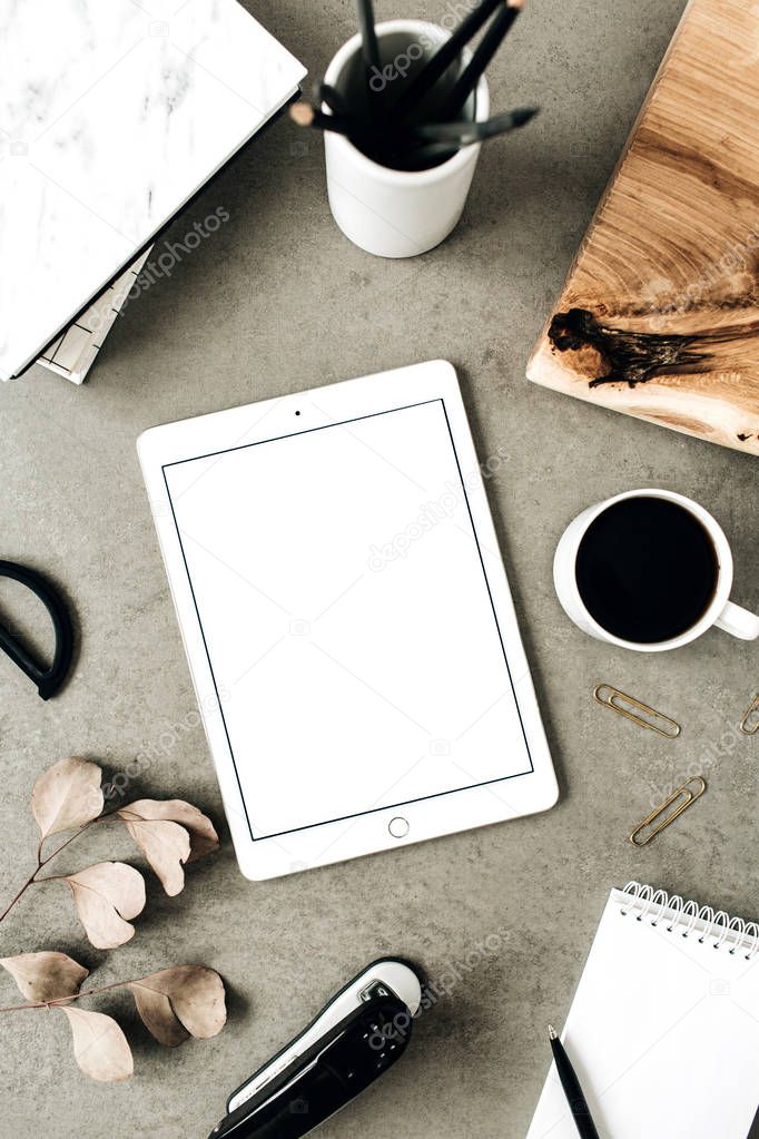 Flat lay of tablet with copy space screen mock up. Top view home office desk workspace decorated with eucalyptus, wooden board and stationery. Social media / blog / website mockup concept.