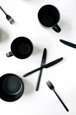 Siyah mutfak eşyaları: çatal, bıçak, kupalar, kase beyaz arka plan üzerinde. Flatlay, üstten görünüm modern mutfak konsepti.