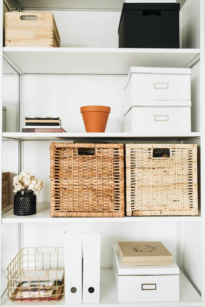 Modern home office cabinet interior design concept. White storage shelves rack with boxes, flowers, decorations.
