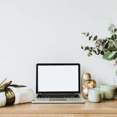 Blogger, serbest ev ofis resepsiyon çalışma alanı. Sahte ahşap masaüstü ekranı olan dizüstü bilgisayar okaliptüs kokulu, hediye kutusu, mum beyaz zemin üzerine dekore edilmiştir. Blog, Web sitesi, sosyal medya kahraman üstbilgi şablonu.