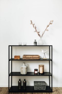 Modern İskandinav iç tasarım konsepti. Çekmeceler, pamuk şubeler, vazo, mumlar ve kuş heykelcik, beyaz duvar ile şık raf.