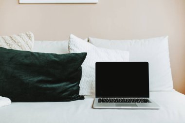 Parlak ev ofis resepsiyon çalışma alanıyla mockup ekran dizüstü bilgisayar. İskandinav modern en az iç tasarım konsepti. Yatak yastık ile bilgisayarda.